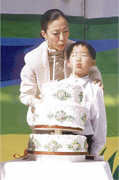 Hoon Sook Nim and Shin Chul Nim blow out the candles on the 1999 Celebration Cake