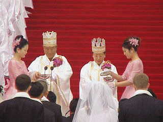 Father and Mother prepare to sprinkle the couples with holy water